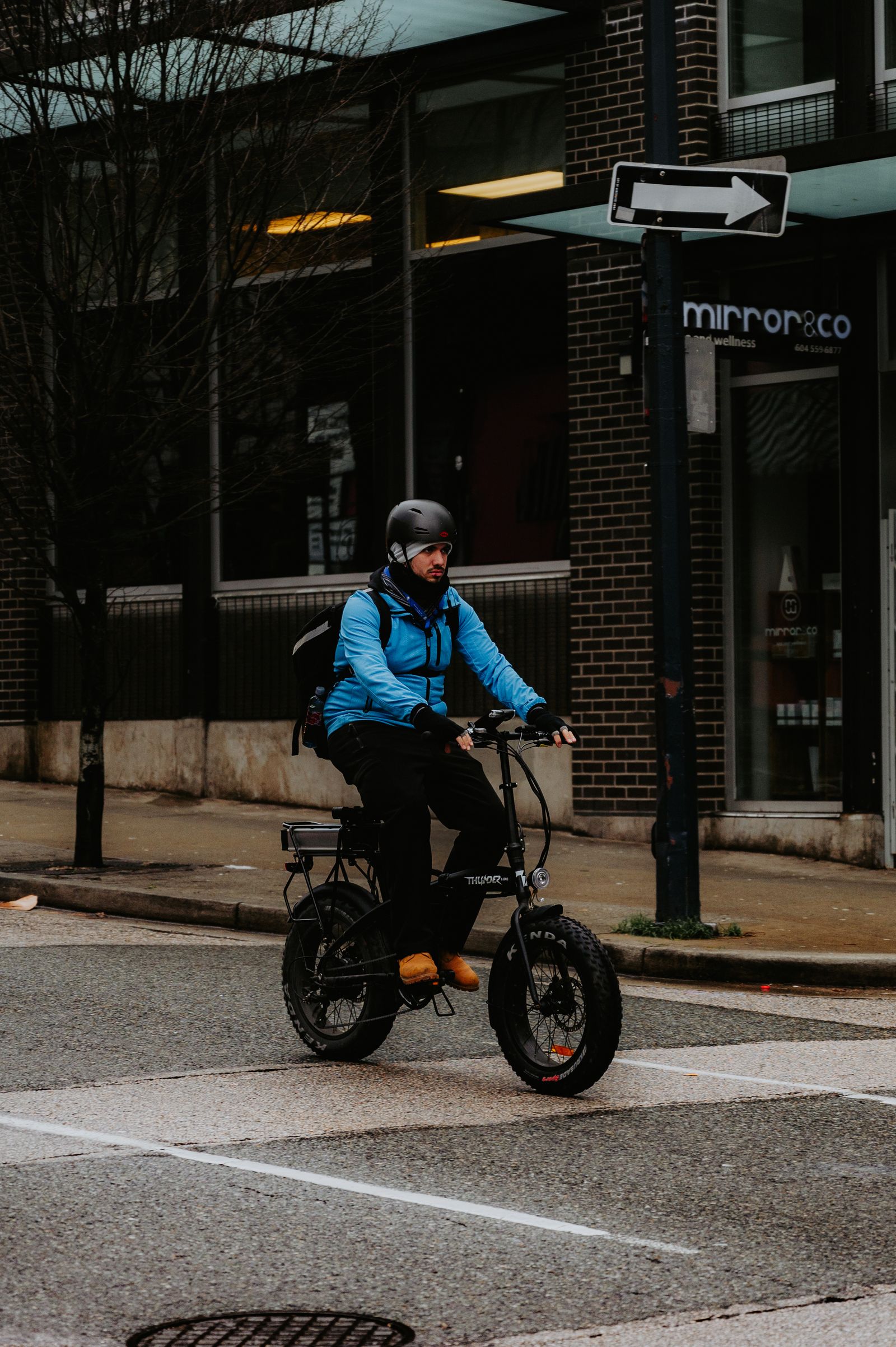 A rider uses an electric bicycle on a city street while wearing protective gear.