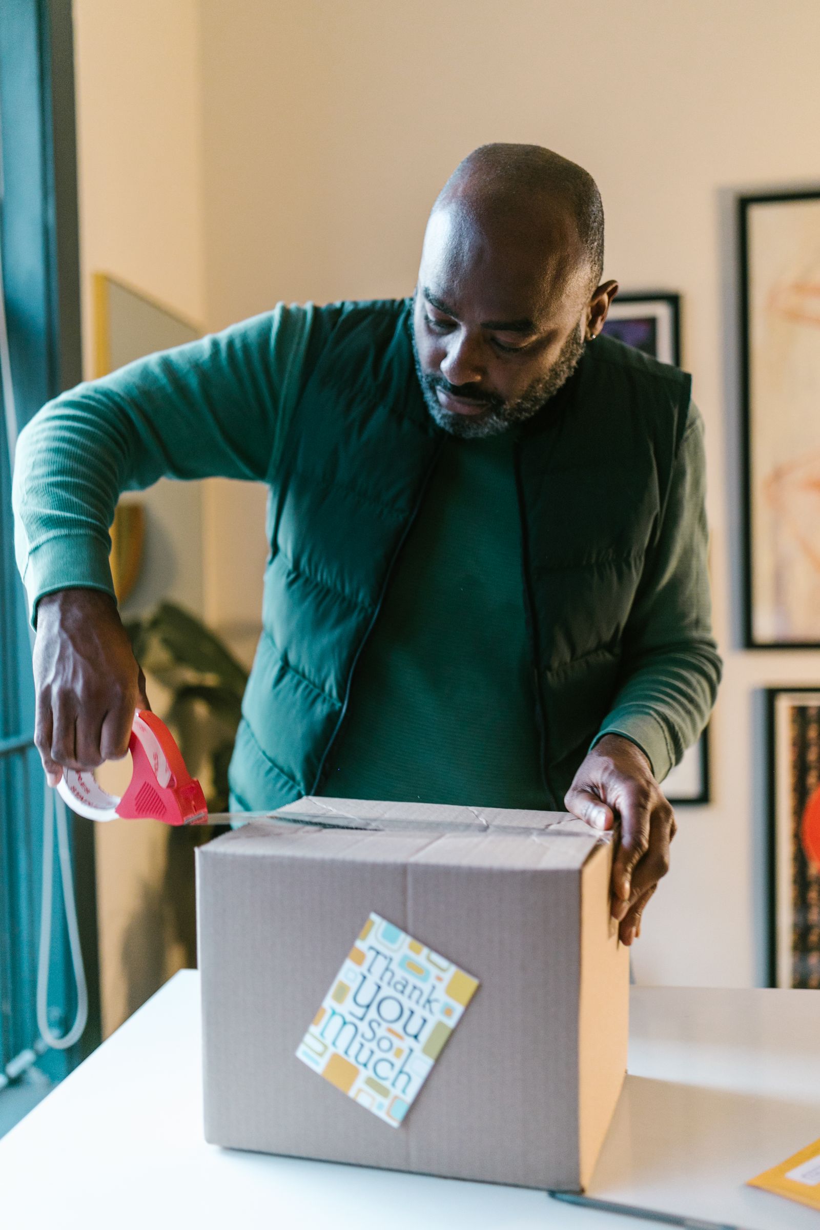 A small-business owner packs an order with a handwritten thank-you card; no label printer is pictured.