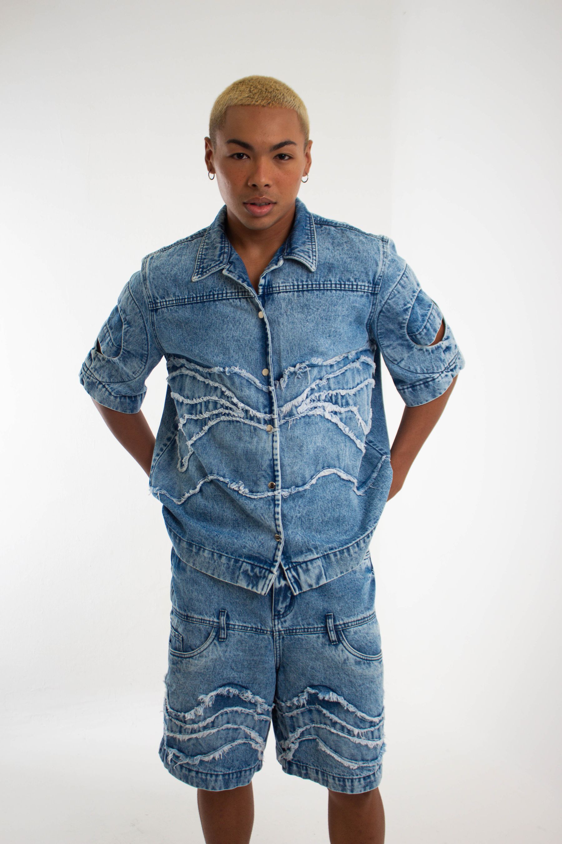 A man wears dark denim jeans and a casual jacket on a city sidewalk; the jeans are not identified as either product.