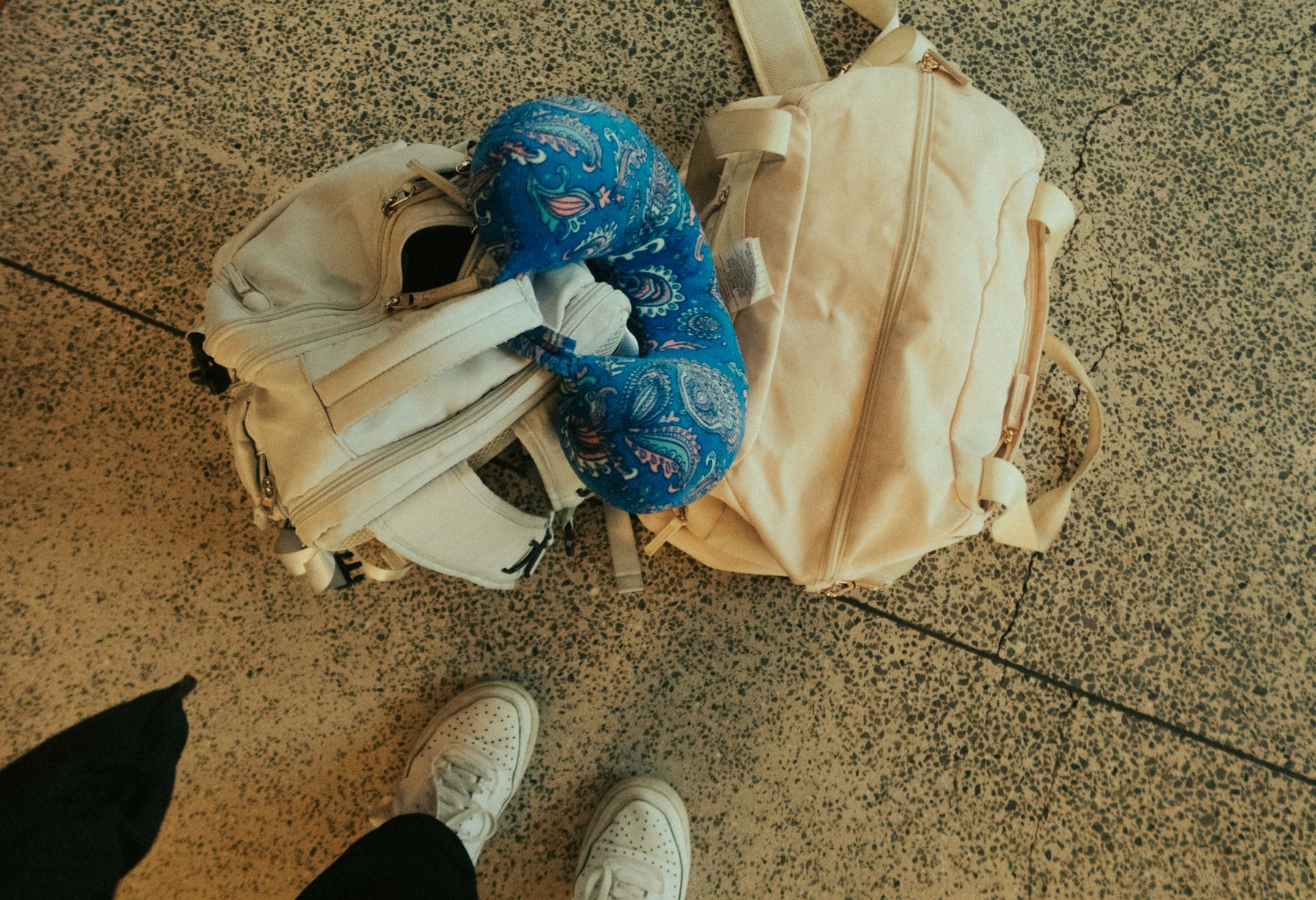 A traveler’s backpack and travel accessories rest on an airport floor; the pack is not identified as either model in this comparison.