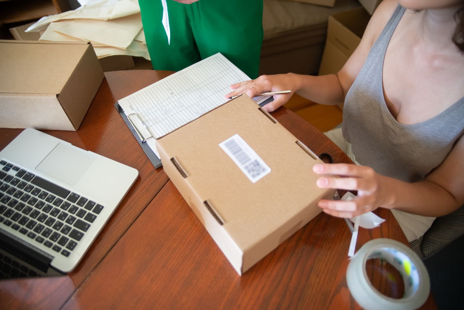 Small-business owners pack customer orders at a table with a laptop.
