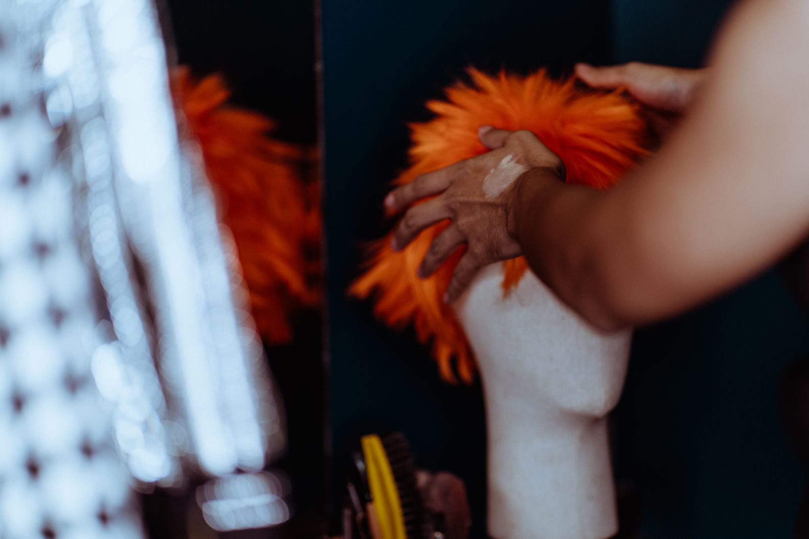 A stylist adjusts a wig on a mannequin, illustrating how cap construction and styling details are assessed.