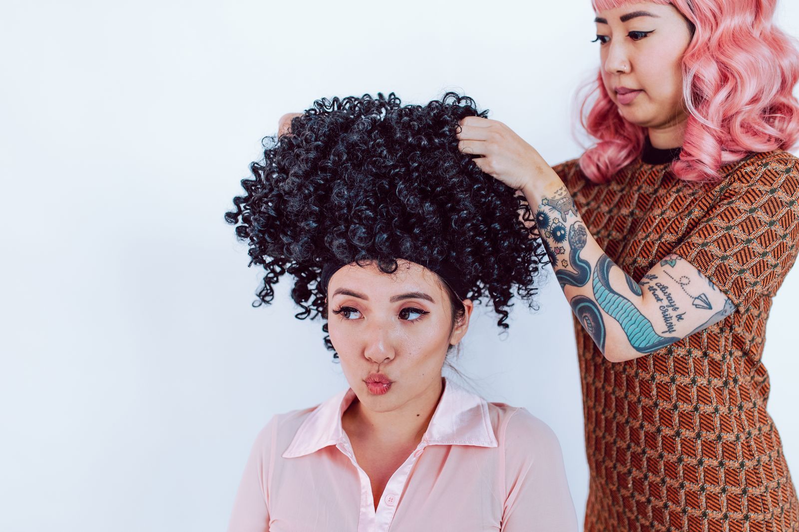 A stylist works on a wig in a salon, illustrating careful preparation before styling.