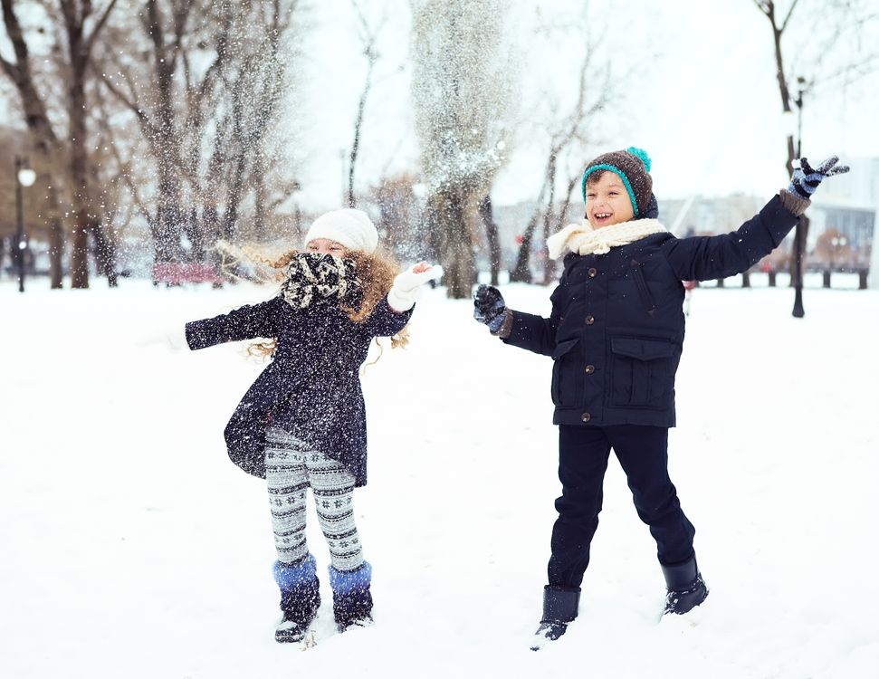 Two children wearing winter clothes play together in the snow; the pictured garments are not identified as products in this guide.